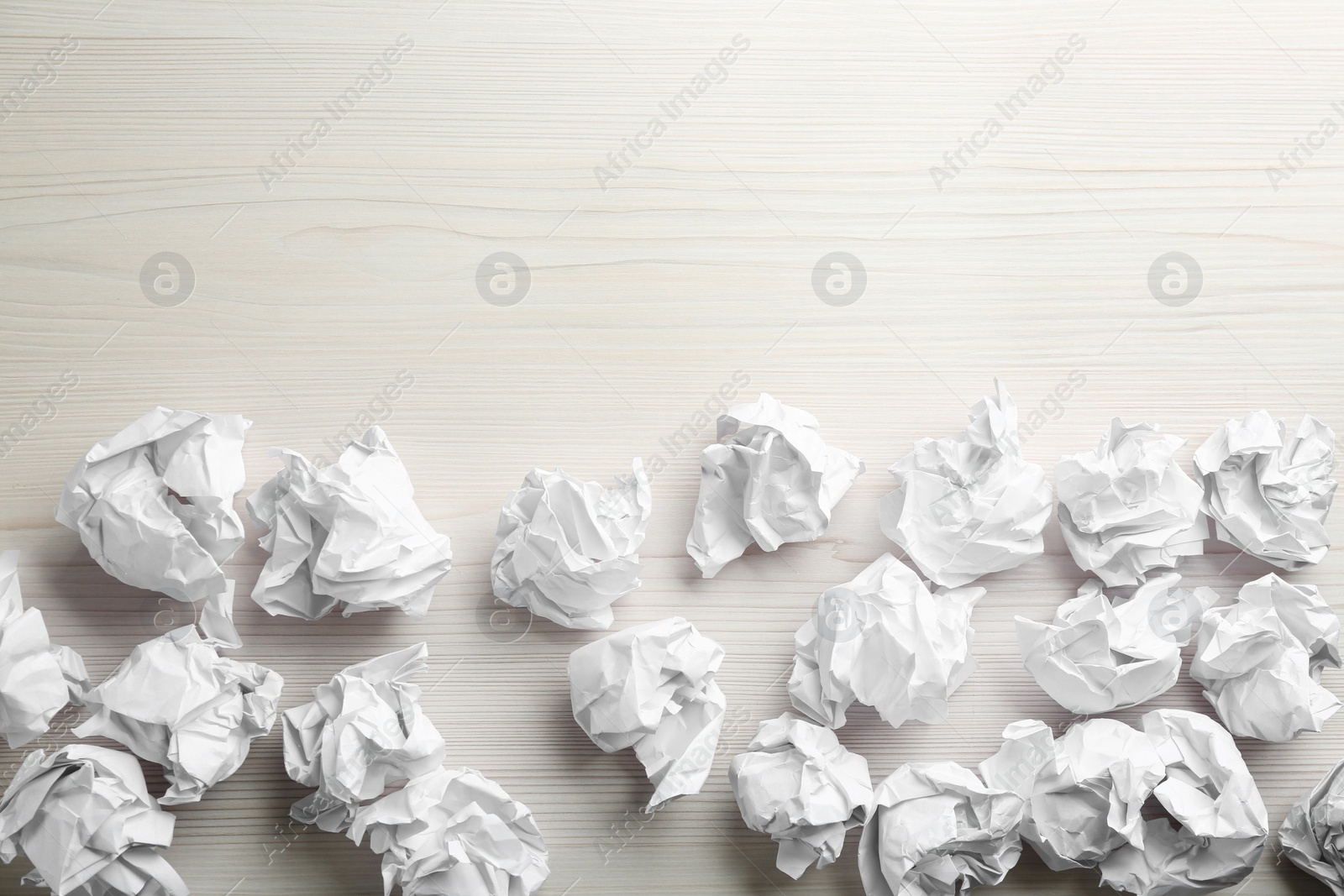 Photo of Crumpled sheets of paper on light wooden background, flat lay. Space for text