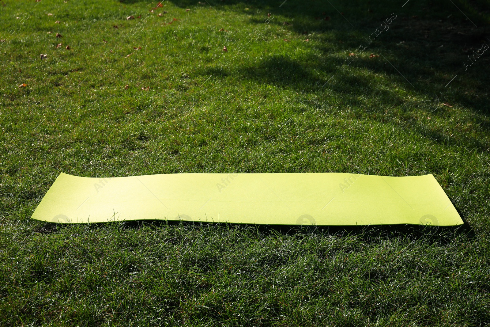 Photo of Bright exercise mat on fresh green grass outdoors