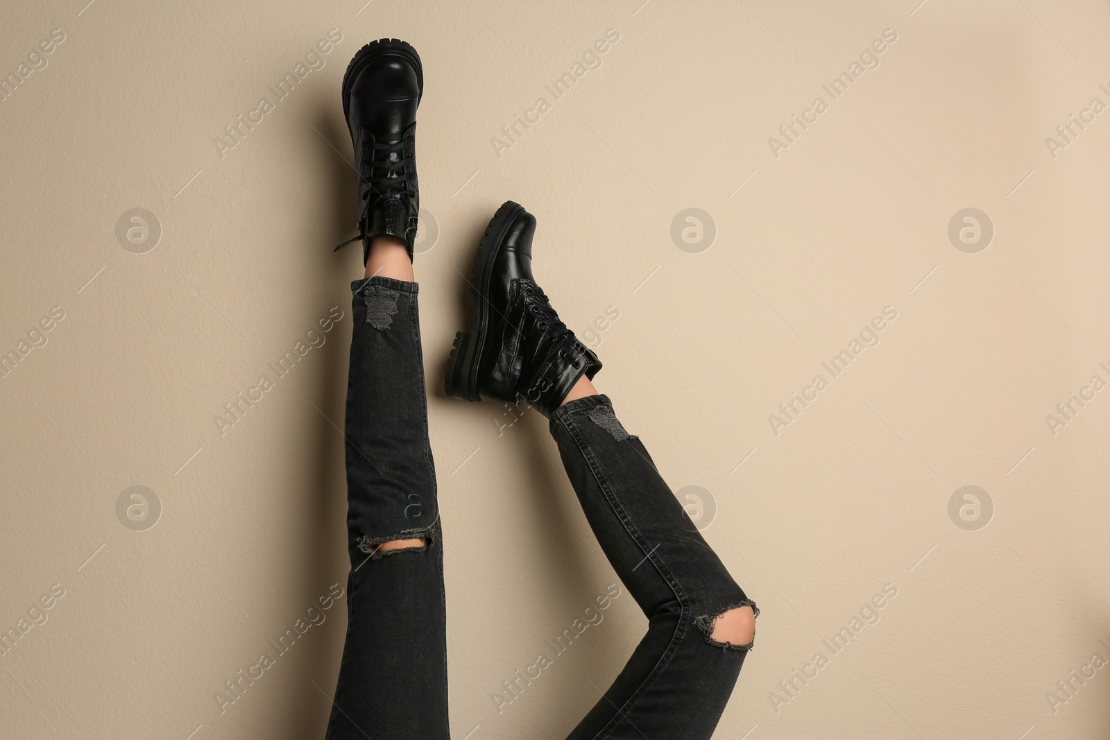 Photo of Woman wearing stylish boots on beige background, closeup