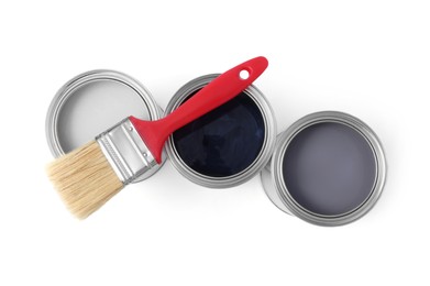 Photo of Cans with different paints and brush on white background, top view