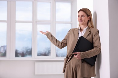Photo of Happy real estate agent with leather portfolio showing new apartment. Space for text