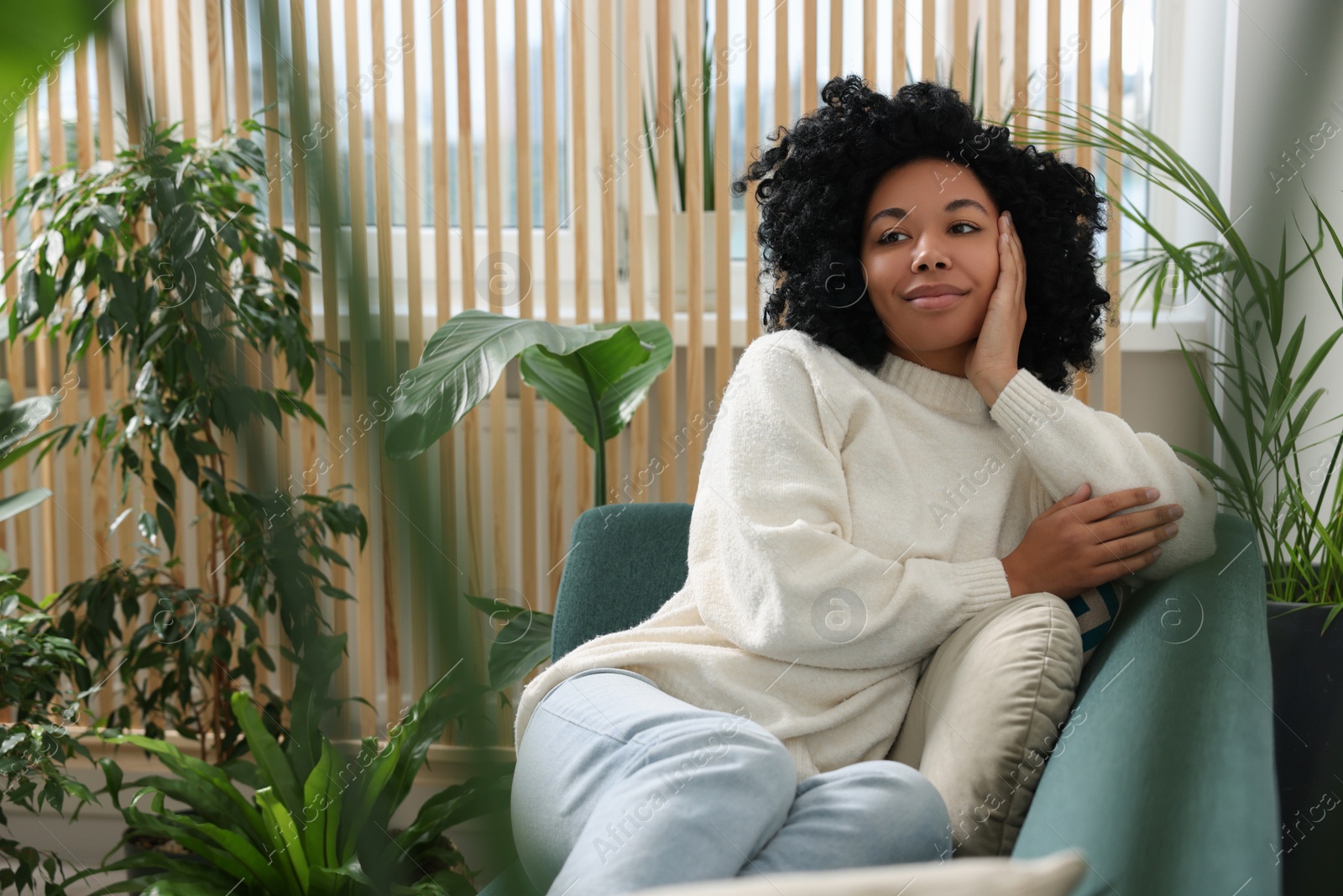 Photo of Woman relaxing on sofa near beautiful houseplants at home