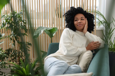 Woman relaxing on sofa near beautiful houseplants at home