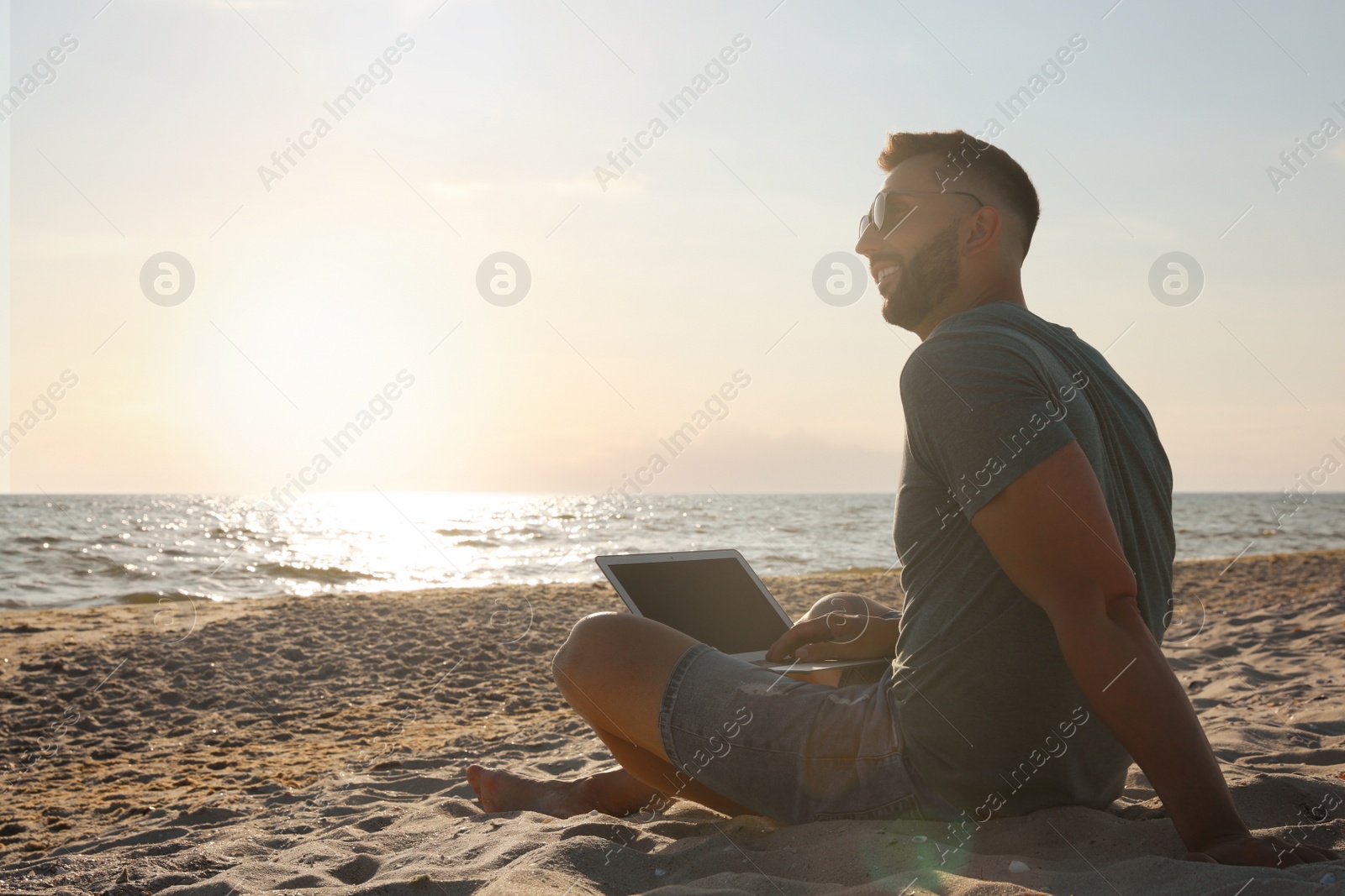 Photo of Man working with laptop on beach. Space for text