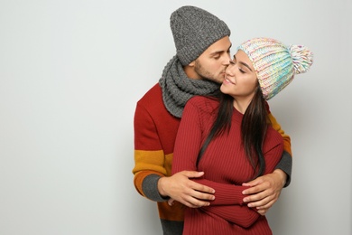 Photo of Young happy couple in warm clothes on light background. Christmas celebration