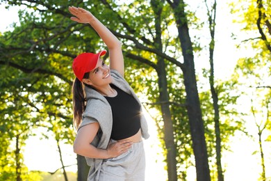 Photo of Young woman doing morning exercise in park. Space for text