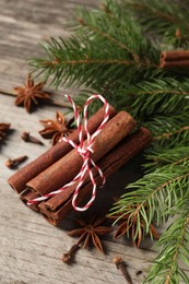 Different spices and fir branches on wooden table, closeup