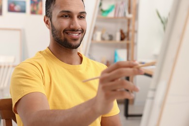 Photo of Young man painting with brush in studio. Creative hobby