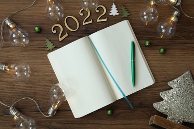 Open planner and Christmas decor on wooden background, flat lay. 2022 New Year aims