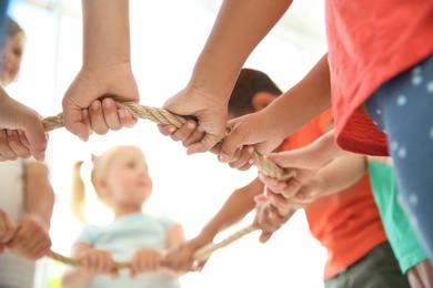 Photo of Little children holding rope on light background, focus on hands. Unity concept