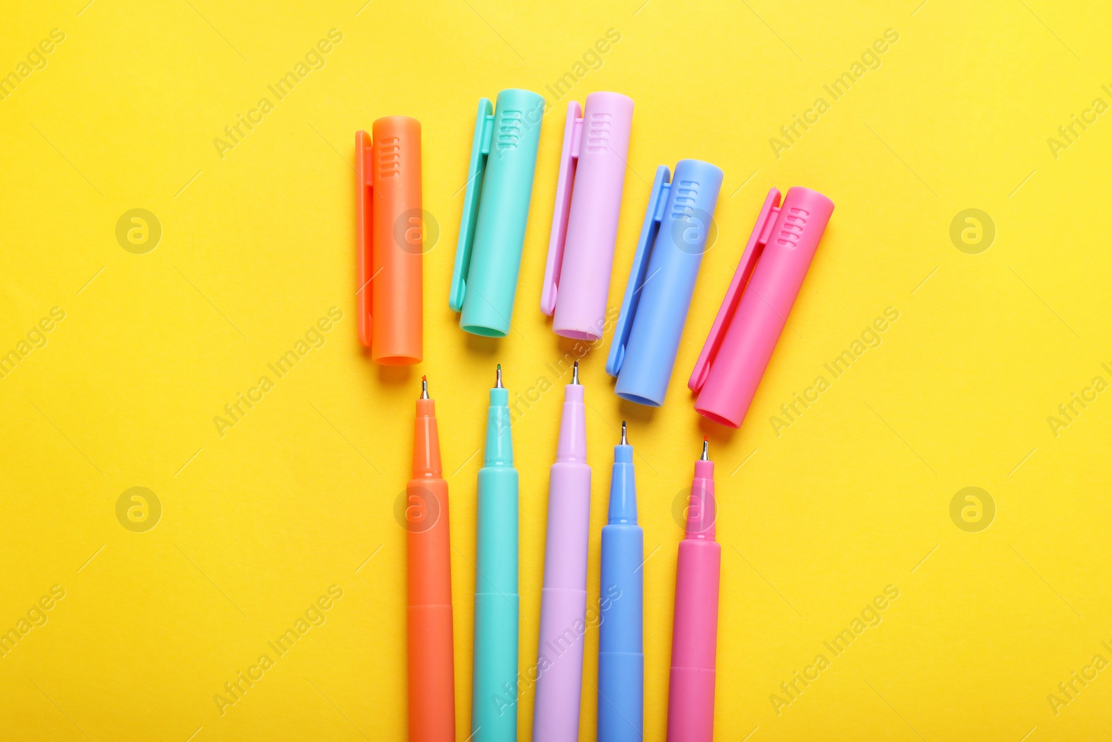 Photo of Many colorful markers on yellow background, flat lay