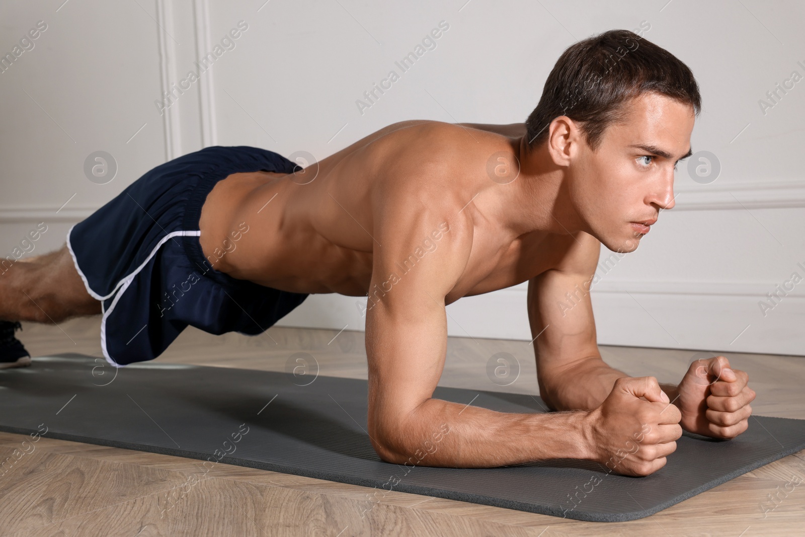 Photo of Handsome man doing plank exercise on floor indoors