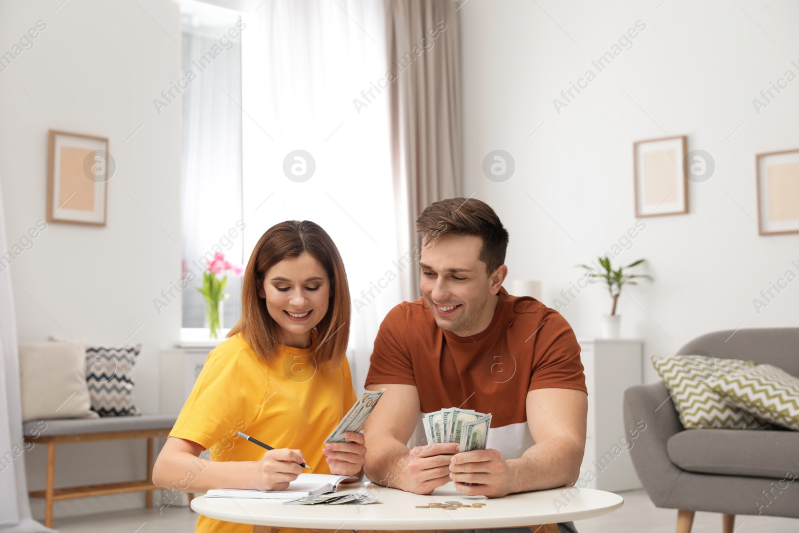 Photo of Couple counting money at table in living room