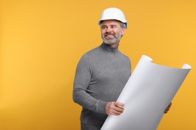 Photo of Architect in hard hat holding draft on orange background. Space for text