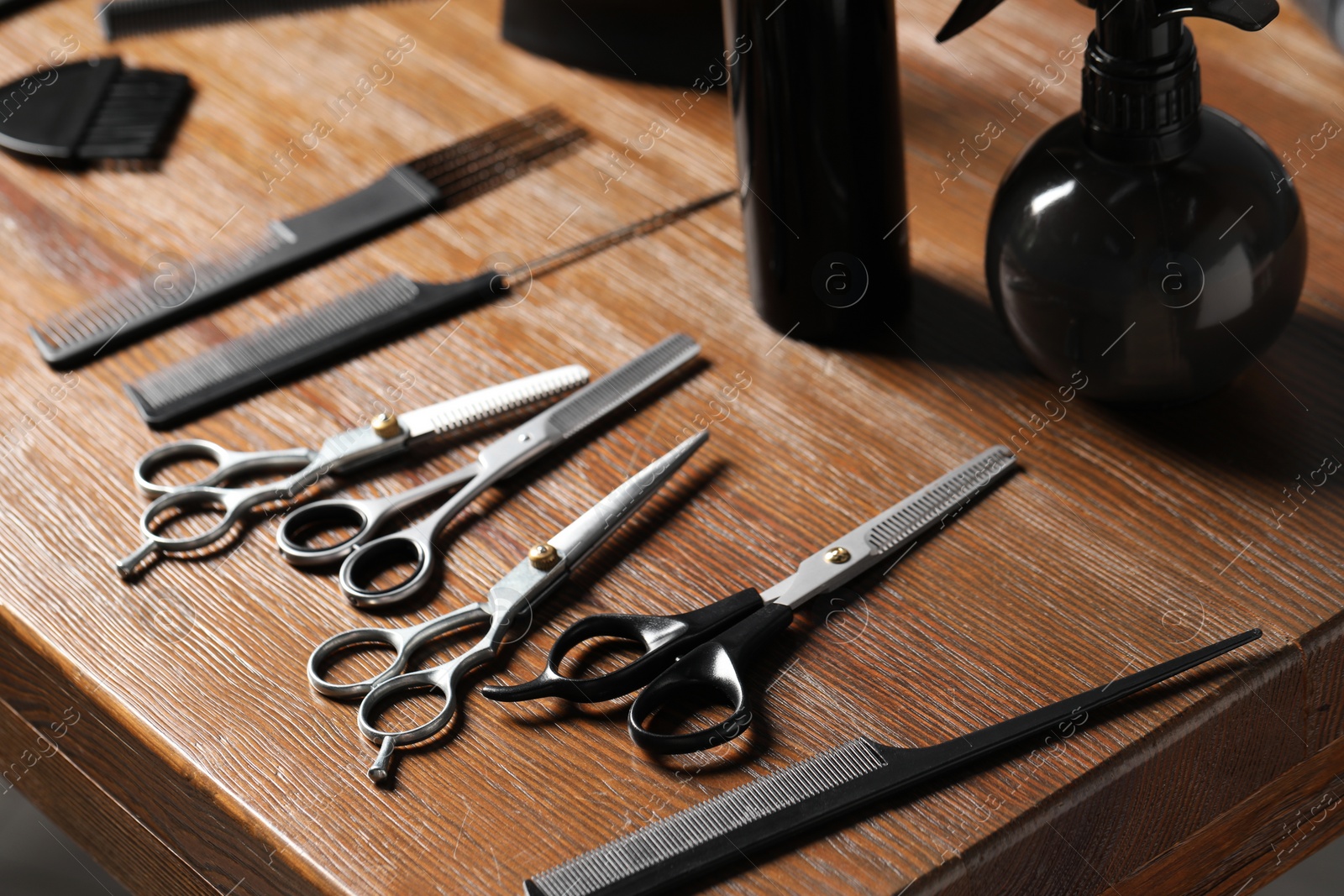 Photo of Hairdresser tools. Different scissors and combs on wooden table, closeup