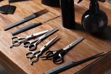 Photo of Hairdresser tools. Different scissors and combs on wooden table, closeup