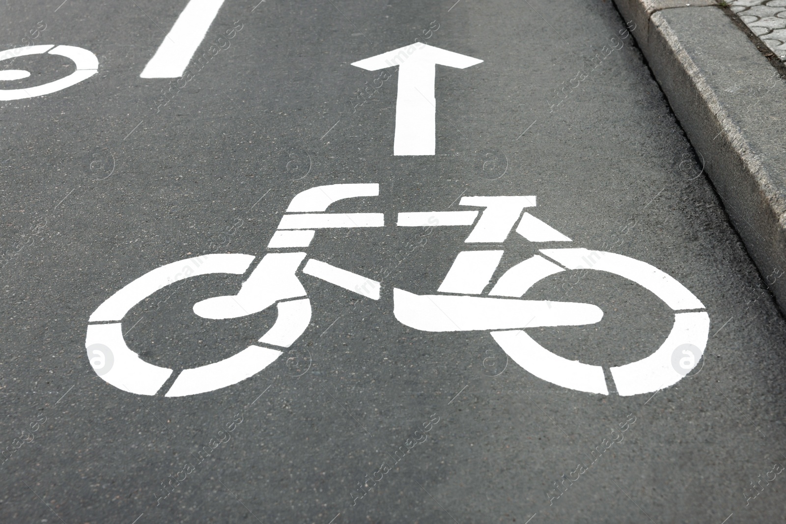 Photo of Bicycle lane with sign and arrow pointing direction on asphalt, closeup