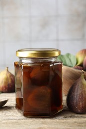 Photo of Jar of tasty sweet jam and fresh figs on wooden table