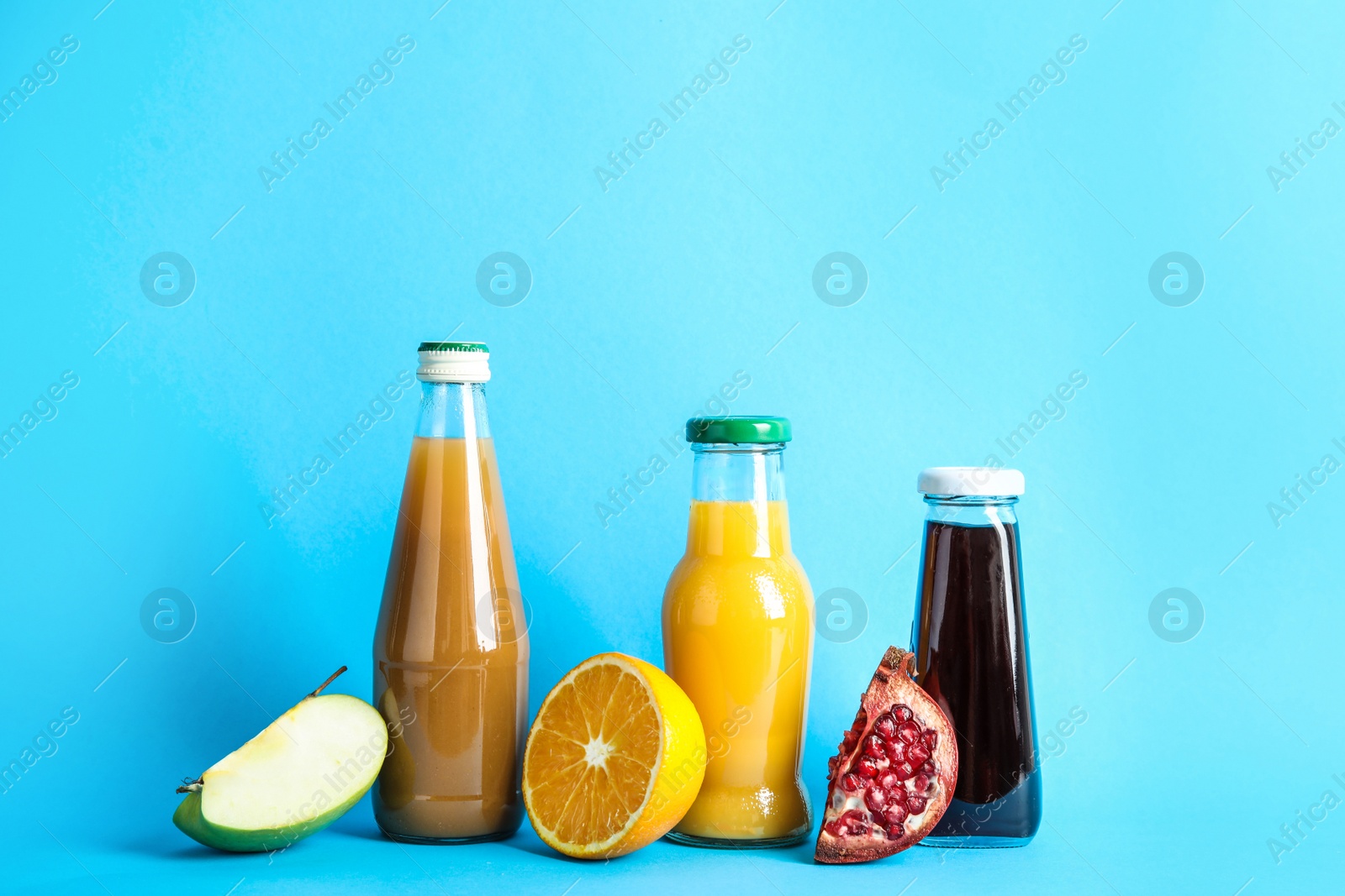 Photo of Bottles with different juices and fresh fruits on color background