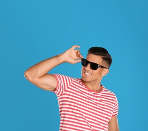 Handsome man wearing sunglasses on blue background