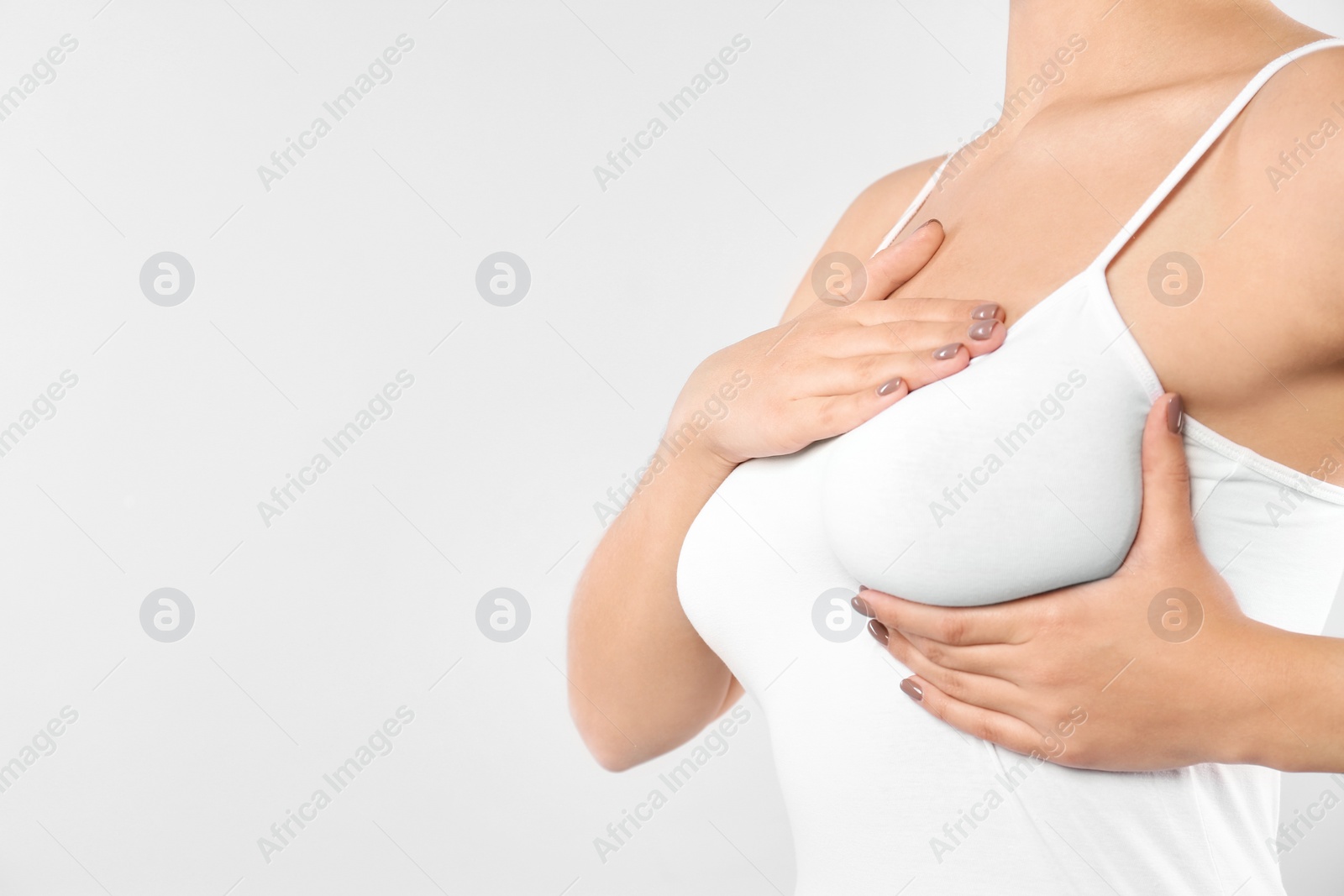 Photo of Woman checking her breast on white background, closeup. Space for text