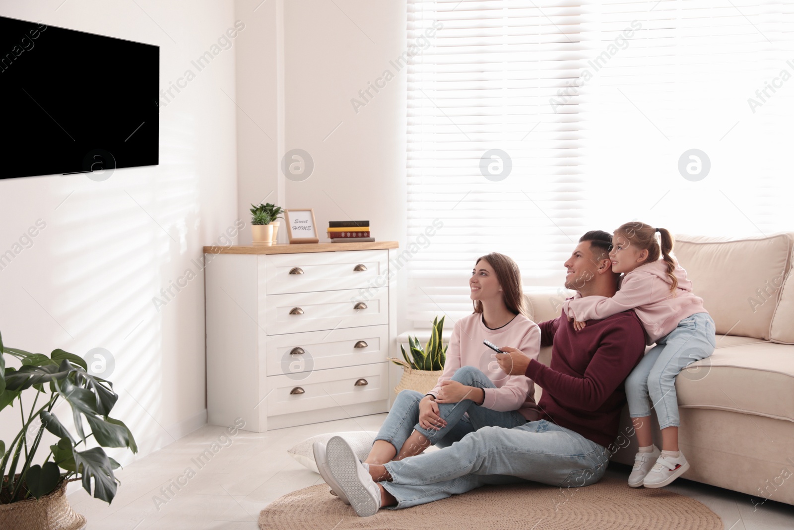 Photo of Happy family watching TV on floor at home