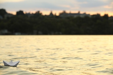 Paper boat floating on water outdoors. Space for text