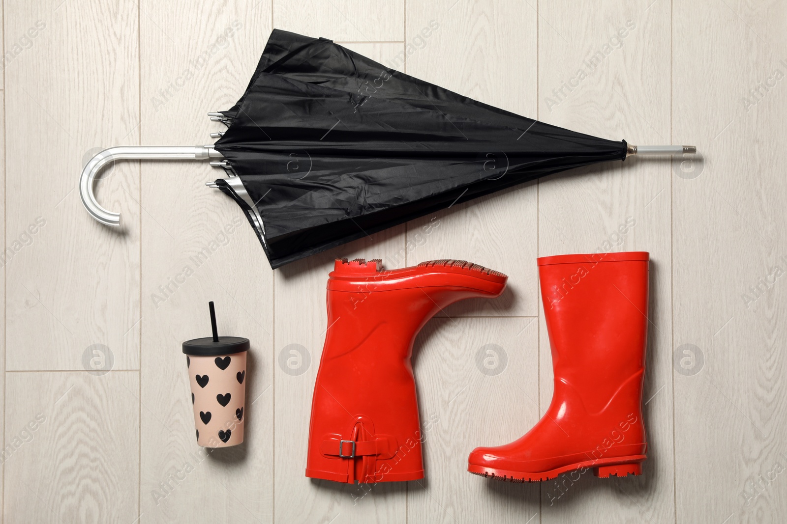 Photo of Flat lay composition with umbrella and rubber boots on wooden background