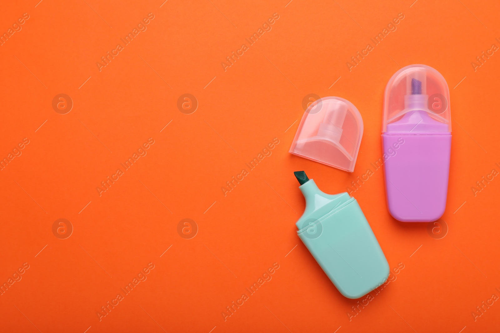 Photo of Two colorful markers on orange background, flat lay. Space for text
