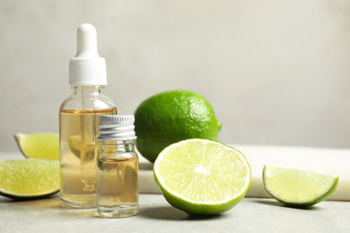 Photo of Lime essential oil and cut citrus fruits on light table