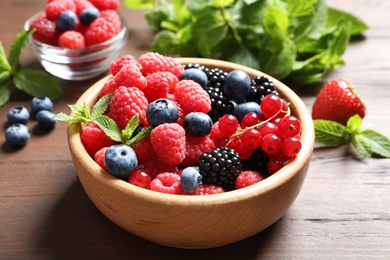 Bowl with raspberries and different berries on wooden table