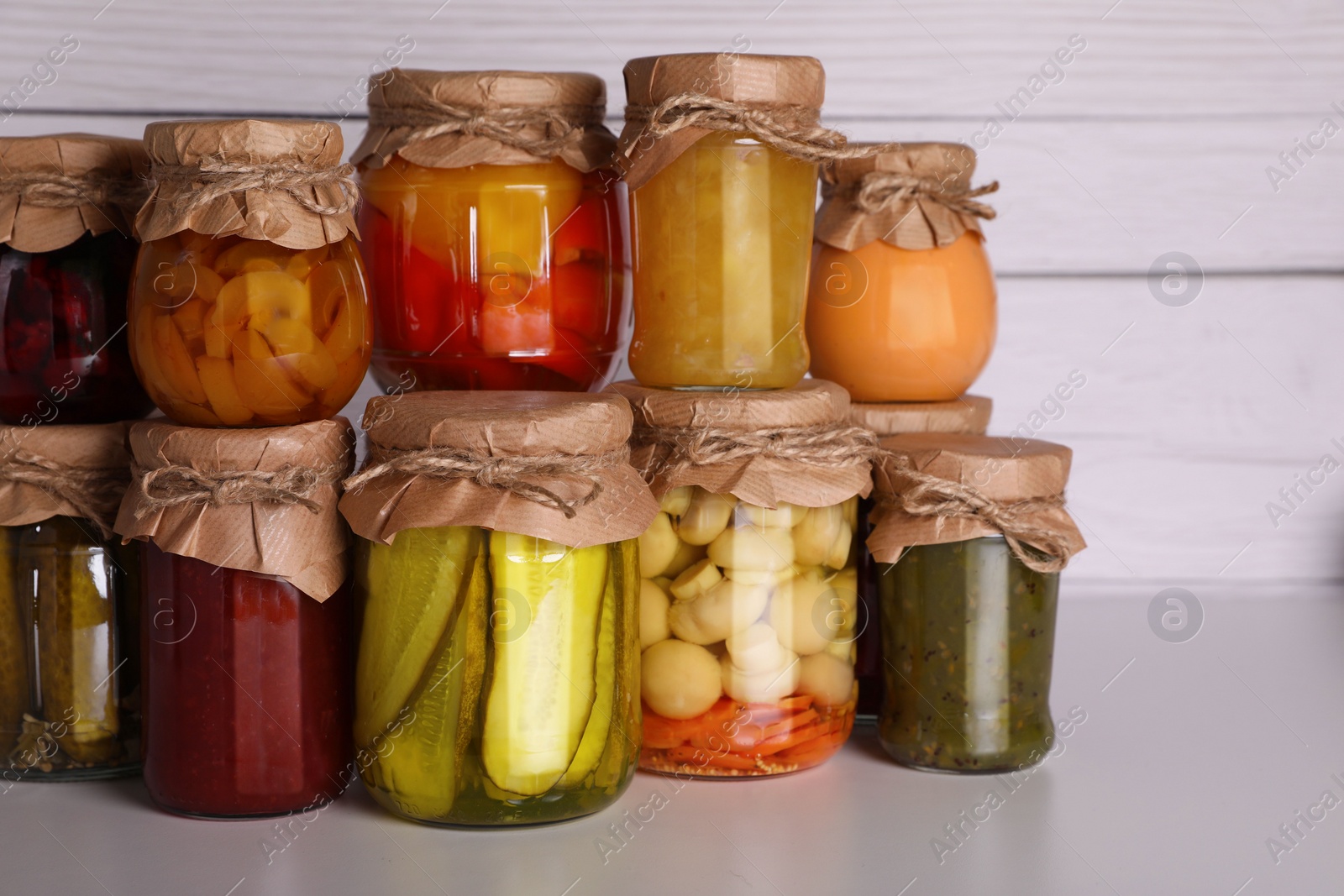 Photo of Many jars with different preserved products on light grey table