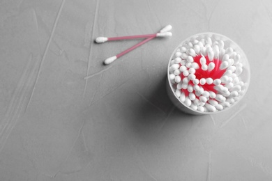 Plastic container with cotton swabs on grey background, top view. Space for text