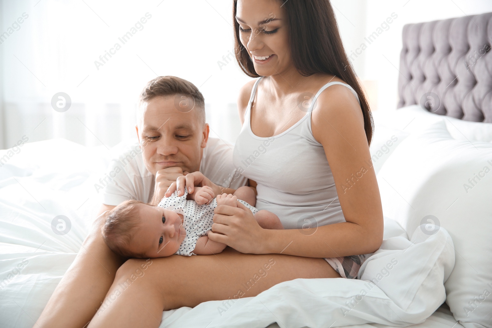 Photo of Happy couple with their newborn baby on bed