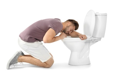Young man vomiting in toilet bowl on white background