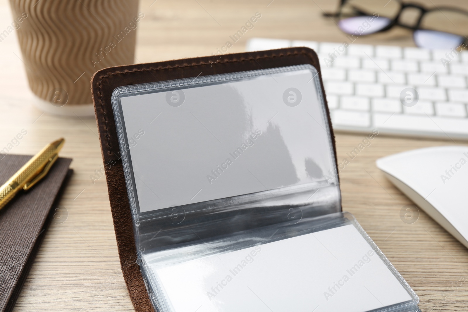 Photo of Leather business card holder with blank cards on wooden table, closeup