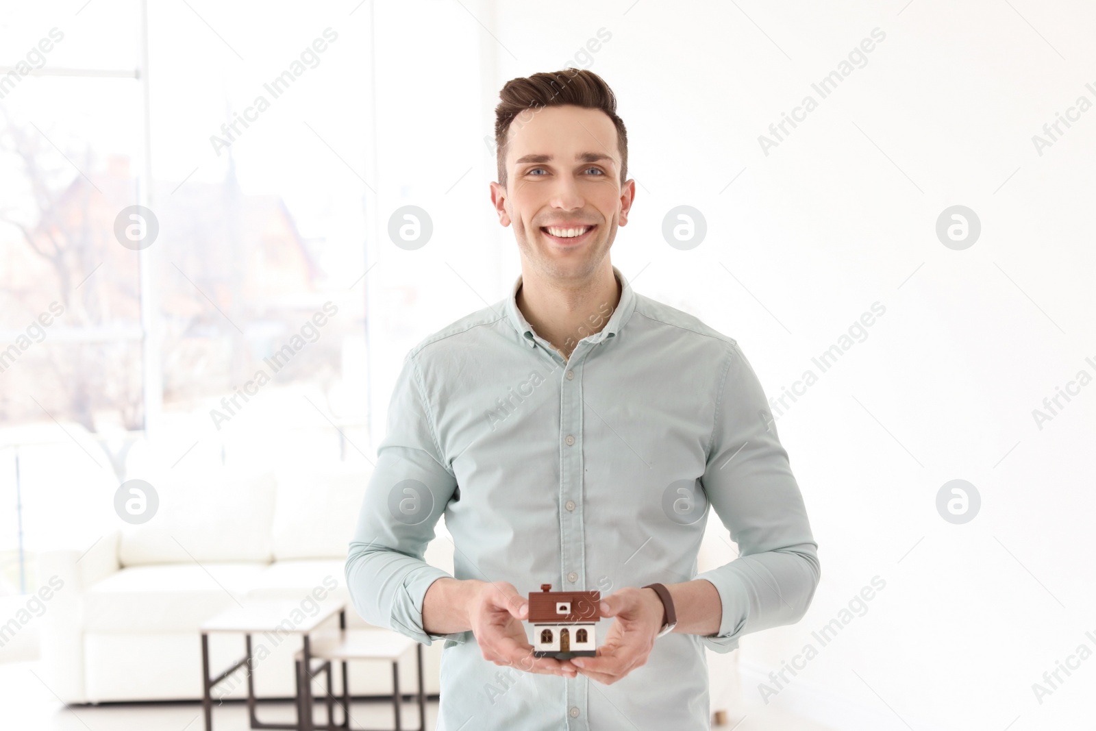 Photo of Male real estate agent with house model indoors