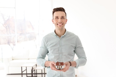 Male real estate agent with house model indoors
