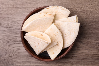 Photo of Bowl with corn tortillas on wooden background, top view. Unleavened bread