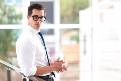 Photo of Handsome young man in stylish clothes with glasses indoors. Space for text