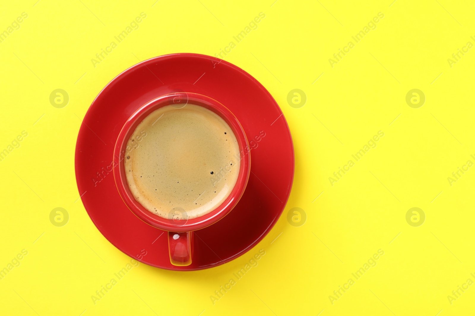 Photo of Tasty coffee in cup on yellow background, top view. Space for text