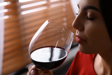 Photo of Woman with glass of luxury red wine indoors, closeup view. Space for text