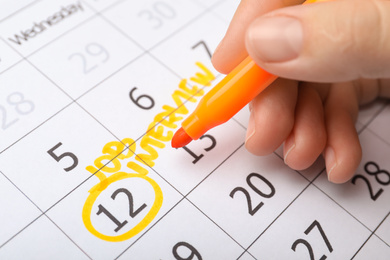 Woman marking date of job interview in calendar, closeup