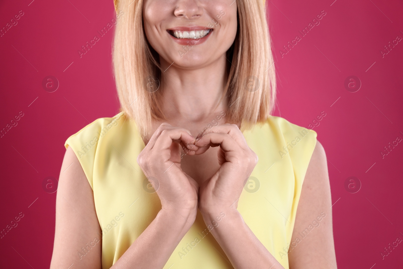 Photo of Woman making heart with her hands on color background, closeup