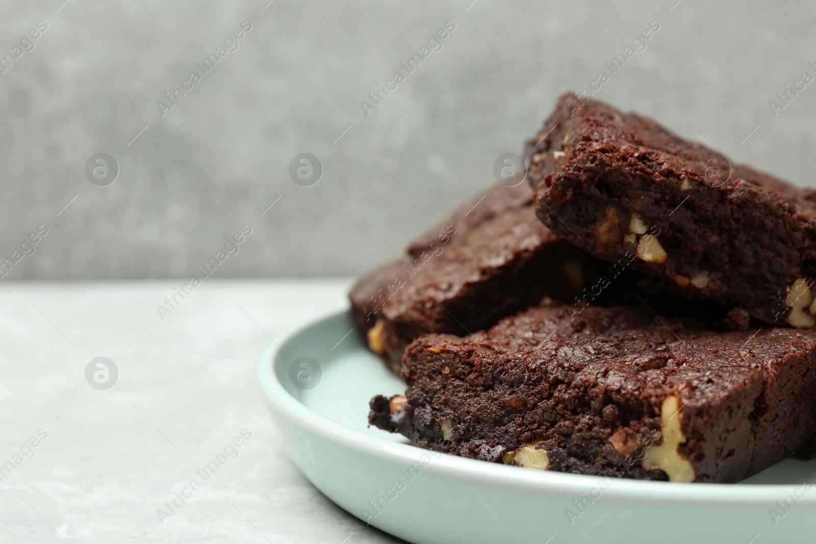 Photo of Delicious chocolate brownies with nuts on light grey table, closeup. Space for text