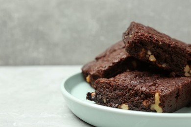 Photo of Delicious chocolate brownies with nuts on light grey table, closeup. Space for text