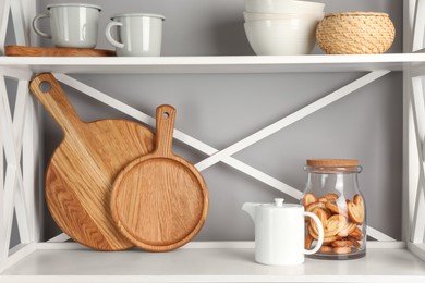 Photo of Wooden cutting boards, kitchen utensils and french palmier cookies on shelving unit