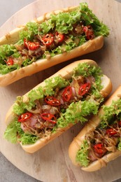 Photo of Tasty hot dogs with chili, lettuce and sauce on grey textured table, top view