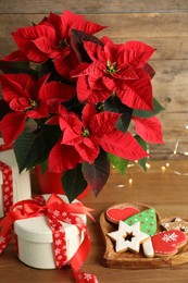 Poinsettia (traditional Christmas flower), gift boxes and cookies on wooden table