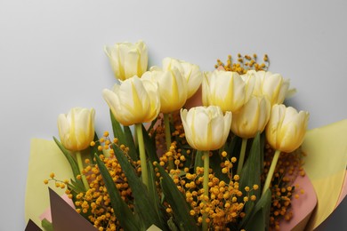 Bouquet with beautiful tulips and mimosa flowers on light grey background, top view